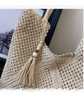 Detailed close-up of straw beach tote with hollow weave pattern and wood bead tassel
