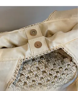 Detail of premium golden magnetic closure and fine woven texture on beige straw bag