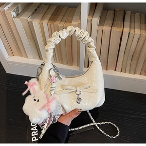 Vue détaillée du sac crème à nœud avec pendentif cœur et porte-clés lapin peluche