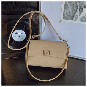 Detail of khaki textured canvas crossbody bag with gold M-logo and metallic studs