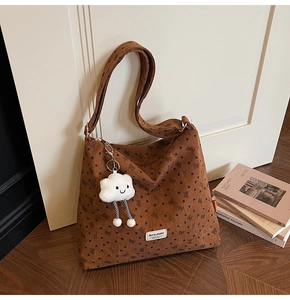 Detailed texture of brown corduroy tote bag with bow pattern and cloud plush charm