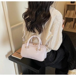 Detailed view of light purple glossy leather bag with gold hardware on a model