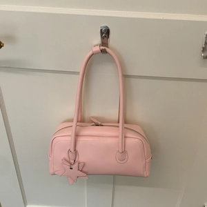 Sac baguette rose rectangulaire avec fermeture éclair et détail de breloque en étoile