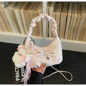 Détail du sac à main plissé rose avec nœud, pendentif cœur et breloque en peluche