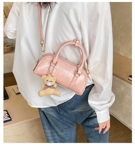 Detail of pink patent leather Boston bag with crinkled texture and cute teddy bear charm
