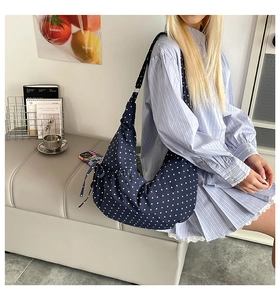 Detail of navy blue polka dot canvas crescent bag with adjustable side drawstrings