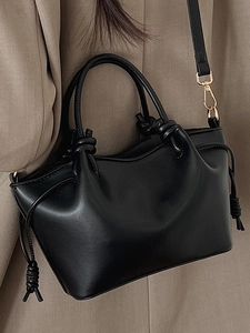 Minimalist black leather crossbody handbag with unique wavy opening and gold hardware