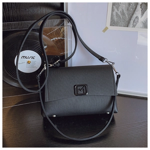 Detailed macro of black textured leather bag featuring a silver metal M buckle and dual straps