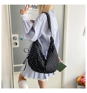 Detail of black polka dot crescent crossbody bag with side drawstring and bow details