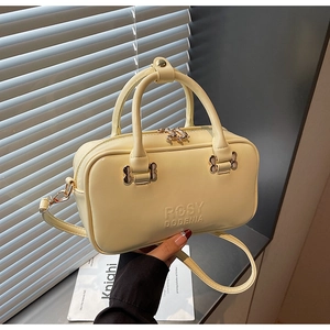 Detail of butter yellow Boston bag with embossed logo and metal butterfly charm