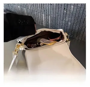 Detail view of the white shoulder bag interior with gold zipper and makeup items