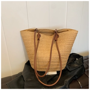 Detailed macro view of woven raffia texture and dark brown leather shoulder strap handle