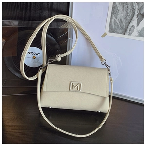 Detail showing the cream small square bag with raised letter M logo and metal hardware