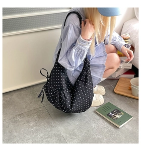 Detail of black polka dot canvas hobo bag showing the side drawstring bow and large capacity