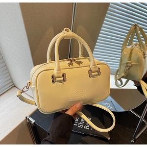 Close-up of beige Boston bag with embossed logo and premium gold-tone metal zipper details