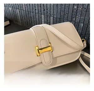 Close-up of elegant gold buckle hardware on a creamy white leather shoulder bag detail