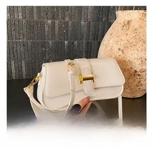 Close-up of white minimalist baguette bag with golden H-shaped hardware and fine leather texture