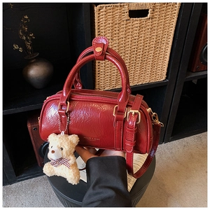 Detail of dark red oil wax leather Boston bag with golden hardware and teddy bear charm