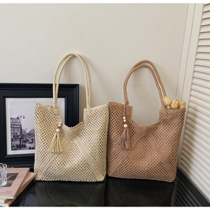 Detail of hand-woven hollow straw tote bag with long tassels and wooden bead accents