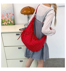 Detail of red and white polka dot canvas crossbody bag with drawstring bow detail