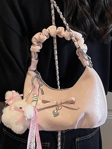 Sac croissant rose avec nœud et poignée plissée porté en bandoulière avec chaîne