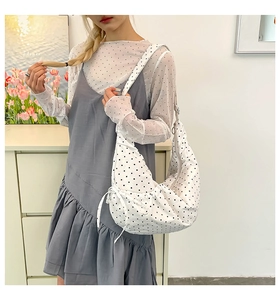 Detailed close-up of a white polka dot canvas hobo bag featuring a decorative side bow tie