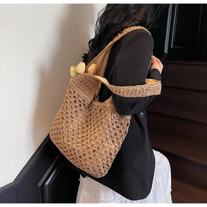 Detailed close-up of large khaki straw tote bag featuring intricate hollow weave patterns