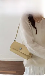 Detail of light yellow leather shoulder bag with lychee texture and silver twist lock