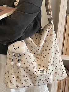 Cream corduroy tote bag with heart patterns and plush cloud charm worn by a model