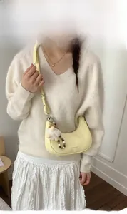 Detailansicht der hellgelben Tasche mit weißem Plüschtier und Perlenanhänger