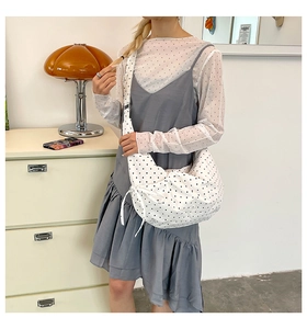 Detail of white polka dot canvas crossbody bag with wide strap and side bow tie knot