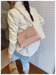 Close-up of pink textured fabric small square bag with metal M logo buckle