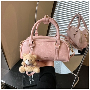 Detail of light pink pleated Boston bag with gold hardware and plush bear charm