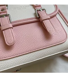 Detail of pink and beige lychee pattern leather handbag with metallic needle buckles
