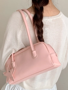 Sac à épaule minimaliste rose en similicuir avec breloque étoile porté par un mannequin