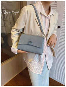 Detail of grey matte shoulder bag with M letter metal buckle worn by model