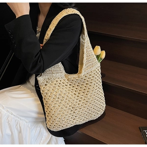 Detail of hollow-out woven texture on a beige straw hobo bag with natural light finish