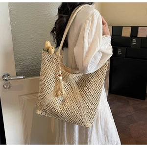 Detail of hollow woven beige tote bag with fringe tassel and white bead decor