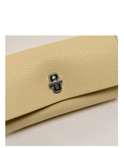 Detailed macro view of the lychee grain leather and silver metal twist lock on the beige bag