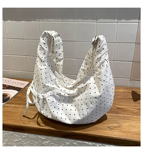Detail view of white polka dot canvas drawstring bag on dark wood table