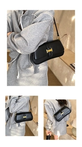 Close-up of black baguette bag with gold H-shaped buckle and leather shoulder strap