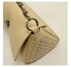 Detail of lychee pattern leather handbag with silver rivets and metal chain strap