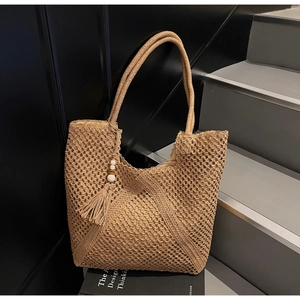 Detailed close-up of handmade woven straw tote bag with tassel and wooden bead charms