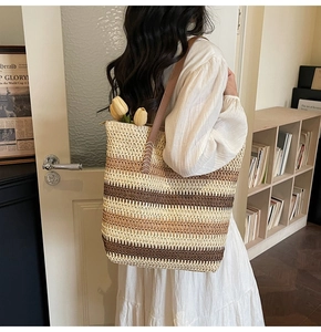 Détail d'un sac cabas en paille tissé à rayures avec des anses en cuir marron pour plage