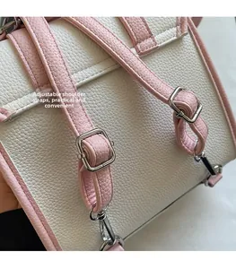 Detail view of pink and white PU leather bag with adjustable silver buckle shoulder strap