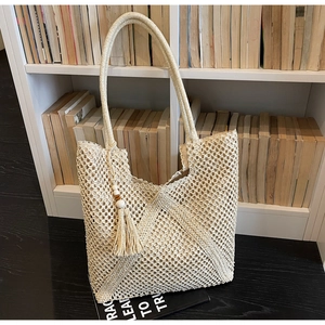 Detail of hand-woven beige tote bag with chic wood-beaded tassels and diamond weave texture