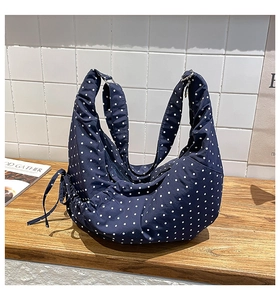 Detail of navy blue polka dot hobo bag with drawstring pleats on a wooden desk