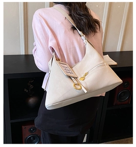 Détail du sac cabas beige avec poche zippée, anneau doré et étiquette tendance