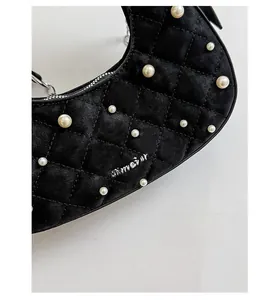 Close-up of black velvet crescent bag with quilted stitching and faux pearl embellishments