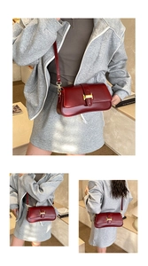 Close-up of a burgundy underarm bag with a golden H-buckle and polished leather finish